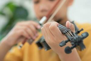 uma pequeno ásia criança jogando e prática violino musical corda instrumento contra dentro lar, conceito do musical Educação, inspiração, adolescente arte escola estudante, seletivo foco. foto