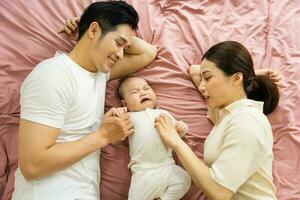 ásia família imagem com bebê deitado dentro cama foto