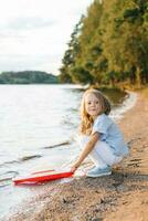 uma menina lançamentos uma barco para dentro a lago foto