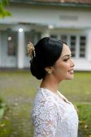 uma jovem indonésio mulher com uma feliz bem sucedido expressão vestindo uma branco kebaya. Kartini's dia conceito. foto