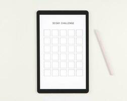 plano deitar do digital tábua com modelo 30 dia desafio em tela, Rosa caneta caneta, isolado em branco fundo. foto