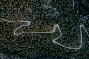 aéreo tiro do uma cheio de curvas estrada em uma montanha dentro uma floresta foto