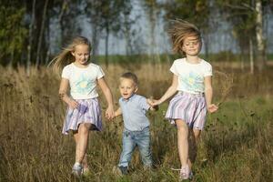 feliz família irmãs e pequeno irmão em uma verão Prado. foto