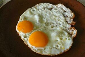 dois frito ovos para saudável café da manhã em uma Castanho prato foto