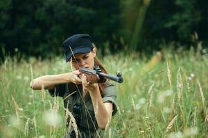 mulher em natureza arma dentro mão Caçando vista verde folhas foto