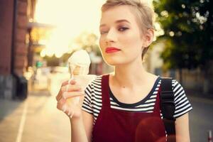 alegre mulher em a rua comendo gelo creme andar verão foto