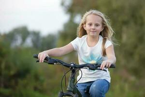 uma menina com grandes cabelo passeios uma bicicleta em uma verão dia. foto