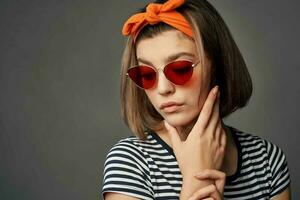 mulher dentro oculos de sol com a laranja curativo em dela cabeça dentro uma listrado camiseta moda foto