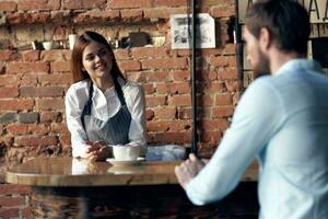 uma mulher uma garçom leva a ordem a partir de uma homem dentro uma cafeteria foto