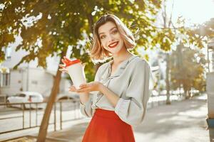 alegre mulher com uma copo do café ao ar livre dentro a verão foto