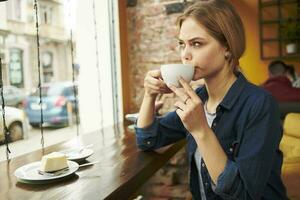bonita mulher sentado às uma cafeteria mesa com uma copo do café café da manhã estilo de vida foto