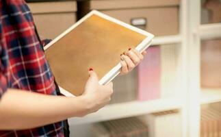fêmea mão segurando uma esvaziar espaço livro dentro dela mão preparando para organizar dentro a Arquivo pasta em a documento armário às a escritório. foto