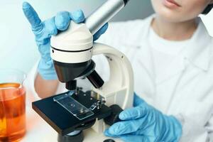 fêmea laboratório assistente dentro uma médico vestido microscópio químico soluções pesquisa foto