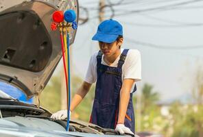 técnico homem Verifica carro ar condicionamento sistema refrigerante recarrega, reparador com monitor ferramenta para Verifica e fixo carro ar condicionador sistema, ar condicionamento reparar foto