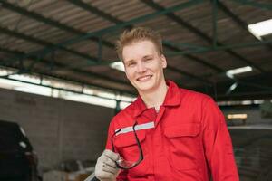 retrato do uma jovem carro mecânico dentro reparar garagem, técnico homem trabalhando dentro auto reparar comprar, carro reparar e manutenção conceitos foto