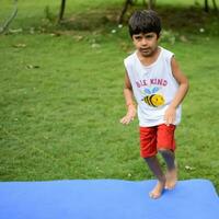 ásia inteligente criança fazendo ioga pose dentro a sociedade parque ar livre, crianças ioga pose. a pequeno Garoto fazendo ioga e meditação exercício. foto