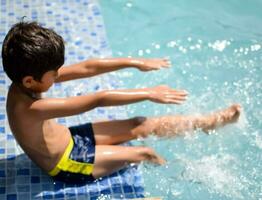 feliz indiano Garoto natação dentro uma piscina, criança vestindo natação traje ao longo com ar tubo durante quente verão Férias, crianças Garoto dentro grande natação piscina. foto