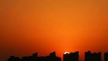 a lindo pôr do sol Visão com a edifícios' silhueta e laranja cor céu Como fundo dentro a cidade foto