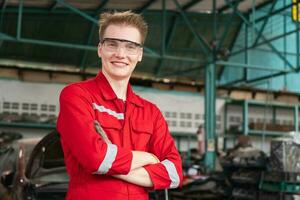 retrato do uma jovem carro mecânico cruzado mãos em pé dentro uma reparar garagem, carro reparar e manutenção conceitos foto