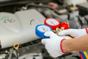 técnico homem Verifica carro ar condicionamento sistema refrigerante recarrega, reparador segurando monitor ferramenta para Verifica e fixo carro ar condicionador sistema, ar condicionamento reparar foto