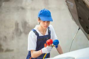 jovem técnico Verifica carro ar condicionamento sistema refrigerante recarrega, reparador segurando monitor ferramenta para Verifica e fixo carro ar condicionador sistema, ar condicionamento reparar foto