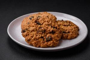 delicioso cozido aveia passas biscoitos em uma Sombrio concreto fundo foto