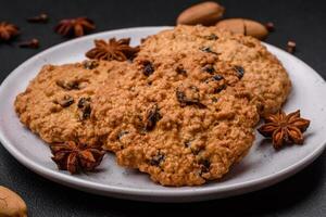 delicioso cozido aveia passas biscoitos em uma Sombrio concreto fundo foto