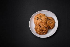 delicioso cozido aveia passas biscoitos em uma Sombrio concreto fundo foto