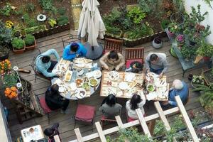 Alto acima ângulo Visão família tendo refeição dentro jardim ensolarado verão dia foto