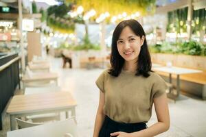 sorridente lindo ásia mulher em pé dentro cantina às compras shopping center. foto