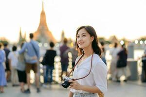 retrato jovem lindo ásia mulher sorridente enquanto viagem às wat uma corrida pôr do sol Visão apontar, Bangkok, tailândia. foto