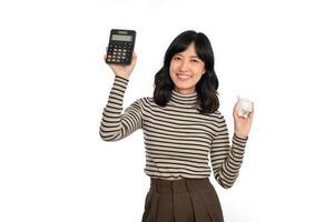 retrato do jovem ásia mulher casual uniforme segurando branco porquinho banco e calculadora isolado em branco fundo, financeiro e banco salvando dinheiro conceito foto