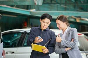 fêmea Gerente e auto mecânico dentro auto reparar comprar, mecânico e jovem mulher cliente falando juntos às a reparar garagem, carro reparar e manutenção conceitos foto