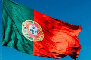 Portugal bandeira isolado em a azul céu acenando dentro a vento foto