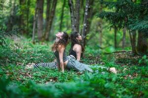 casal do meninas prática ioga dentro a madeiras foto