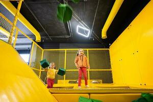 irmãos jogando suave cubos às amarelo Parque infantil parque. irmãs dentro ativo entretenimento. foto