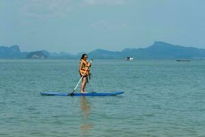 mulher jogando sup borda dentro azul mar dentro verão período de férias foto