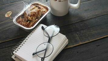 banana bolo em uma Preto de madeira mesa com Nota livro, copos, e café canecas. foto