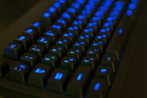 jogos teclado com iluminado chaves. Preto chaves com azul brilhando cartas foto