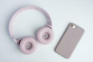 Rosa sem fio fones de ouvido e uma Smartphone em uma branco fundo. música Tempo foto