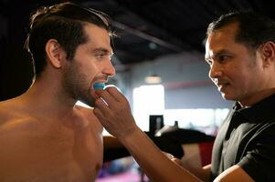 a boxer devo vestem uma dente colarinho antes a luta para evita a risco do prejuízo a partir de dentes confronto quando socado dentro a queixo ou face, muay tailandês, tailandês marcial artes. foto