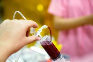 enfermeira mãos é ajustando a seringa para desenhar sangue a partir de a sangue saco para sangue transfusão para doente recém-nascido bebê dentro uma hospital. foto