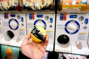 osaka, Japão, 2018 -mão do turista segurando e mostrar cápsula brinquedo em embaçado gashapong vending máquina. gashapong é 1 do vending dispensado por máquina cápsula brinquedos popular dentro Japão. foto