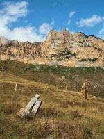 montanha vertical outono panorama com pedra inclinado sem nome lápides. sem nome pedra lápides em a lado da montanha. lápides fez do pedra. stur-digora região. norte ossétia. foto