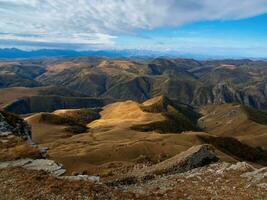 nascer do sol Visão do bermita platô pedras. montanhas em a Beira do uma penhasco dentro a distância em ensolarado manhã. atmosférico panorama com silhuetas do montanhas. karachay-cherkessia, Cáucaso, Rússia. foto