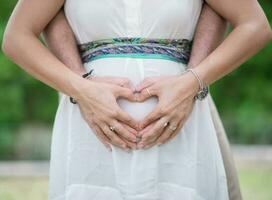 imagem do pais mãos Como uma coração forma em barriga foto