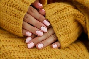fêmea mãos com lindo oval unhas, fosco Rosa manicure fechar-se em uma tricotado suéter fundo. shellac. cópia de espaço foto