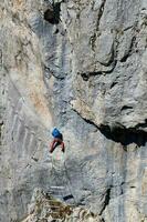 uma pessoa escalada uma através da ferrata rota em uma vertical Rocha muro. Esportes vida dentro a montanhas. ativo vida. alpinista usando apropriado equipamento para segurança. através da ferrata sokolov colocar romanija dentro bih. foto