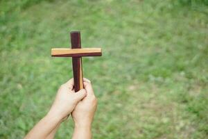 fechar-se mãos aguarde de madeira cruzar, crucifixo ar livre. conceito , cristão adorar. fé, perdão, crença, amor e ter esperança. religioso símbolo do cristandade. foto