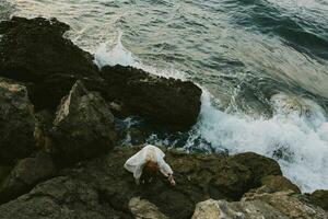 lindo mulher dentro branco Casamento vestir em mar costa molhado cabelo Visão a partir de acima foto